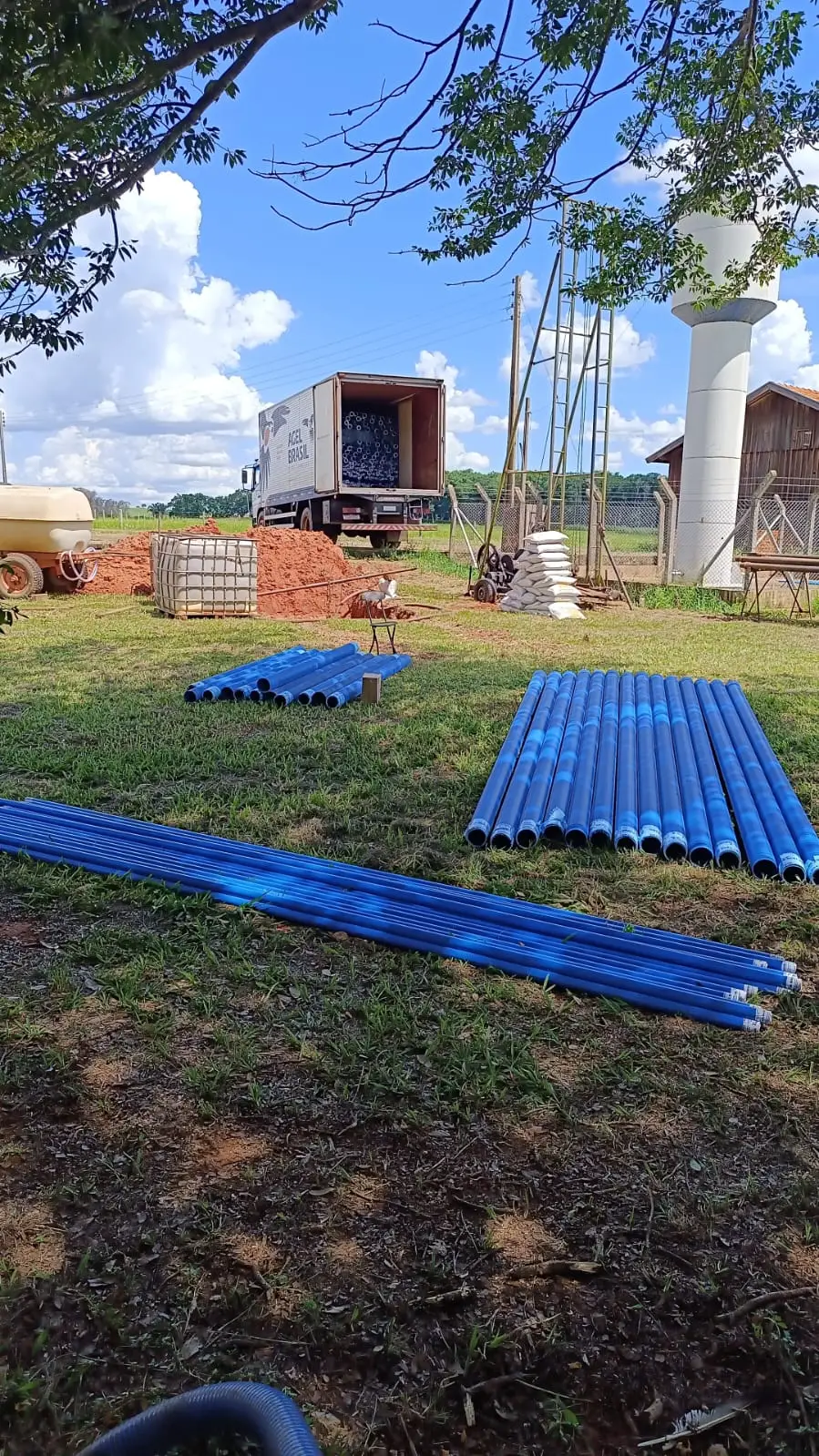 Tubos de revestimento azuis e materiais entregues ao lado de um poço artesiano